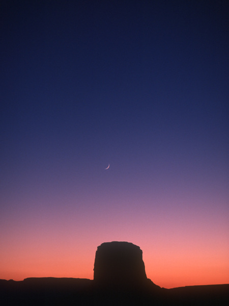 Crescent moon over a butte